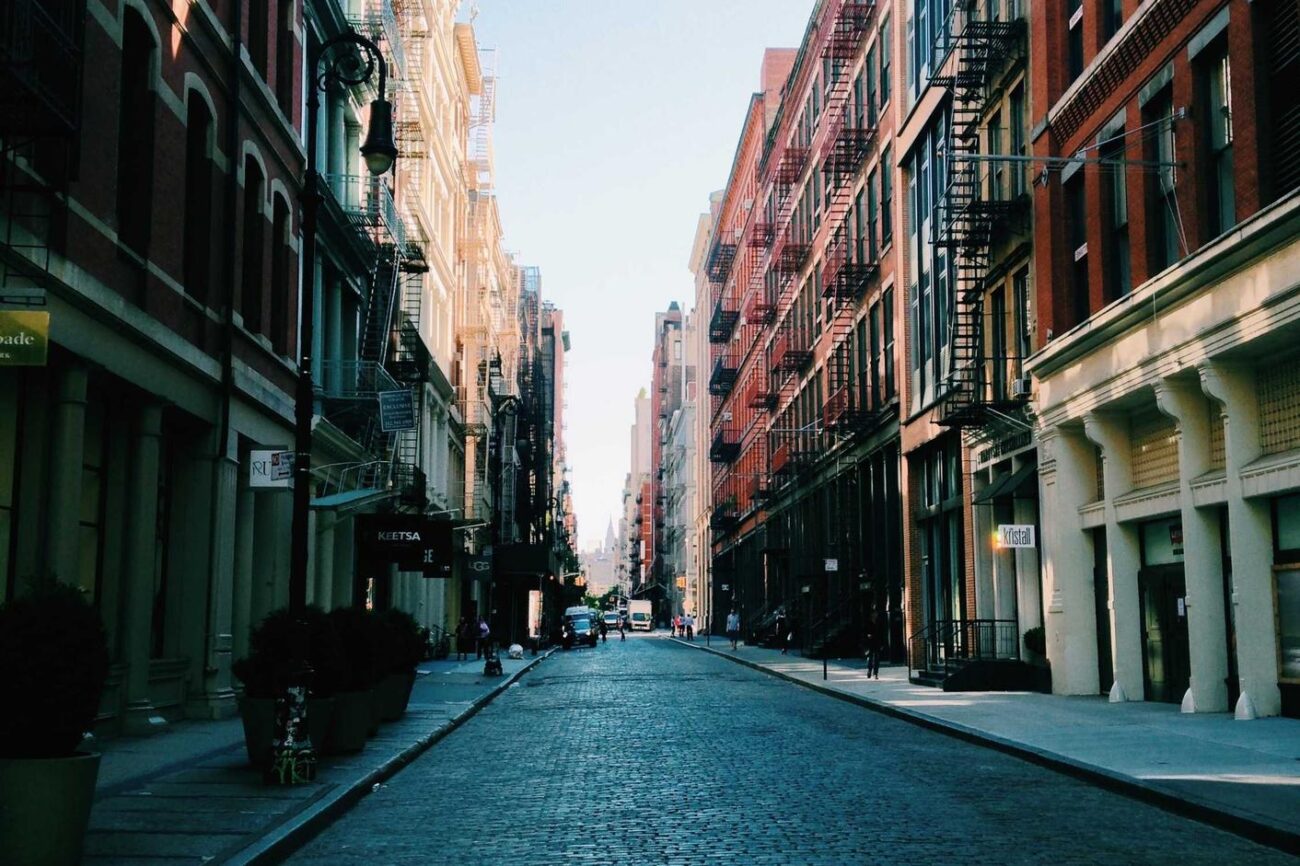 A vibrant city street scene featuring historic buildings, cobblestone pavement, and urban architectu.